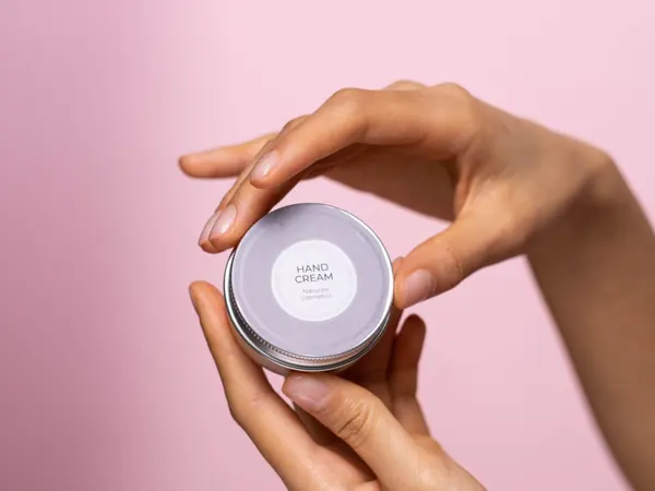 A hand holding a jar of cream