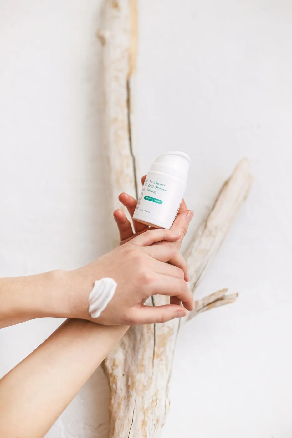Hands holding a bottle of skincare cream
