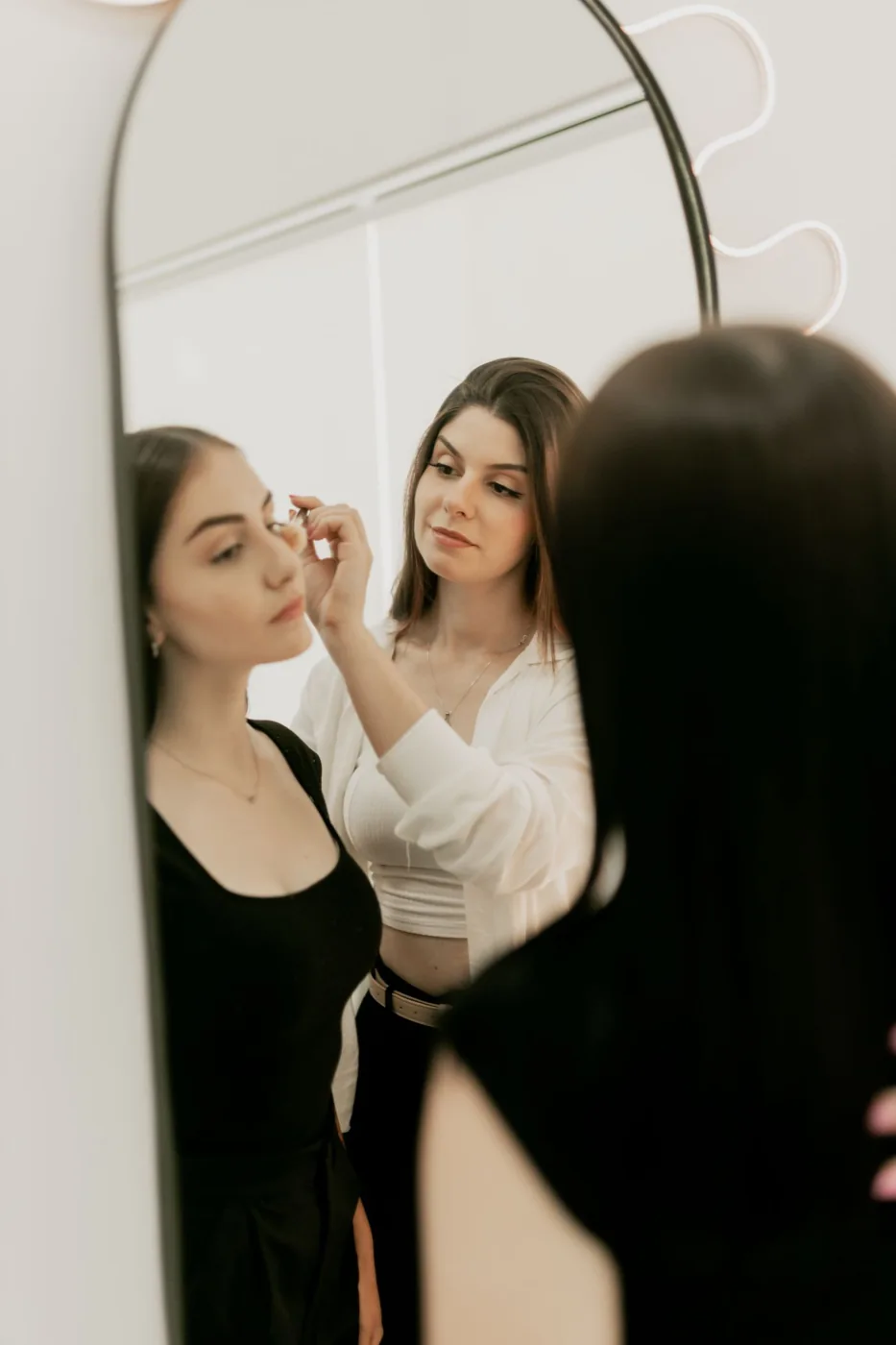 Makeup being applied in front of a vanity mirror