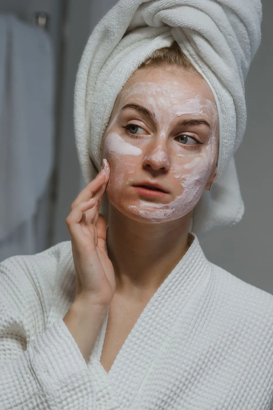 Woman applying face cream during a bathroom routine