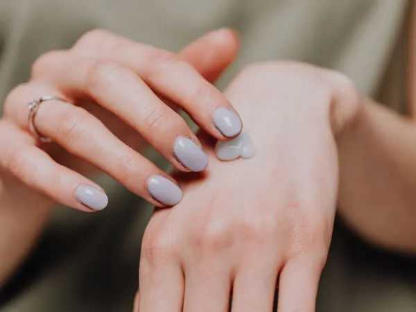 Hands applying cream while wearing a casual shirt