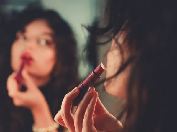 Woman applying lipstick in her mirror