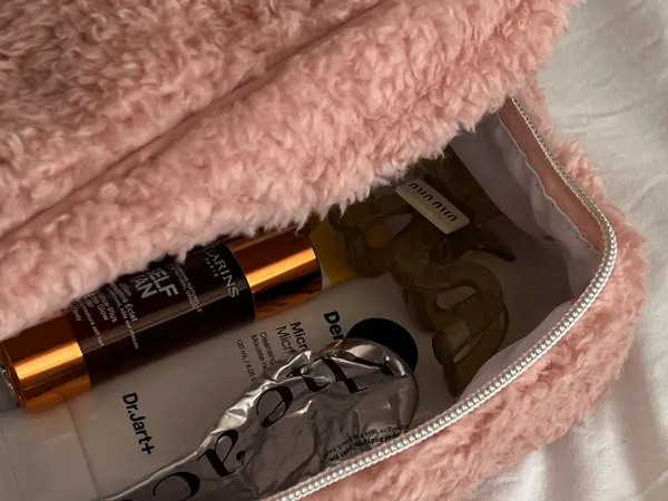 Skincare and cosmetics packed into a pink beauty bag