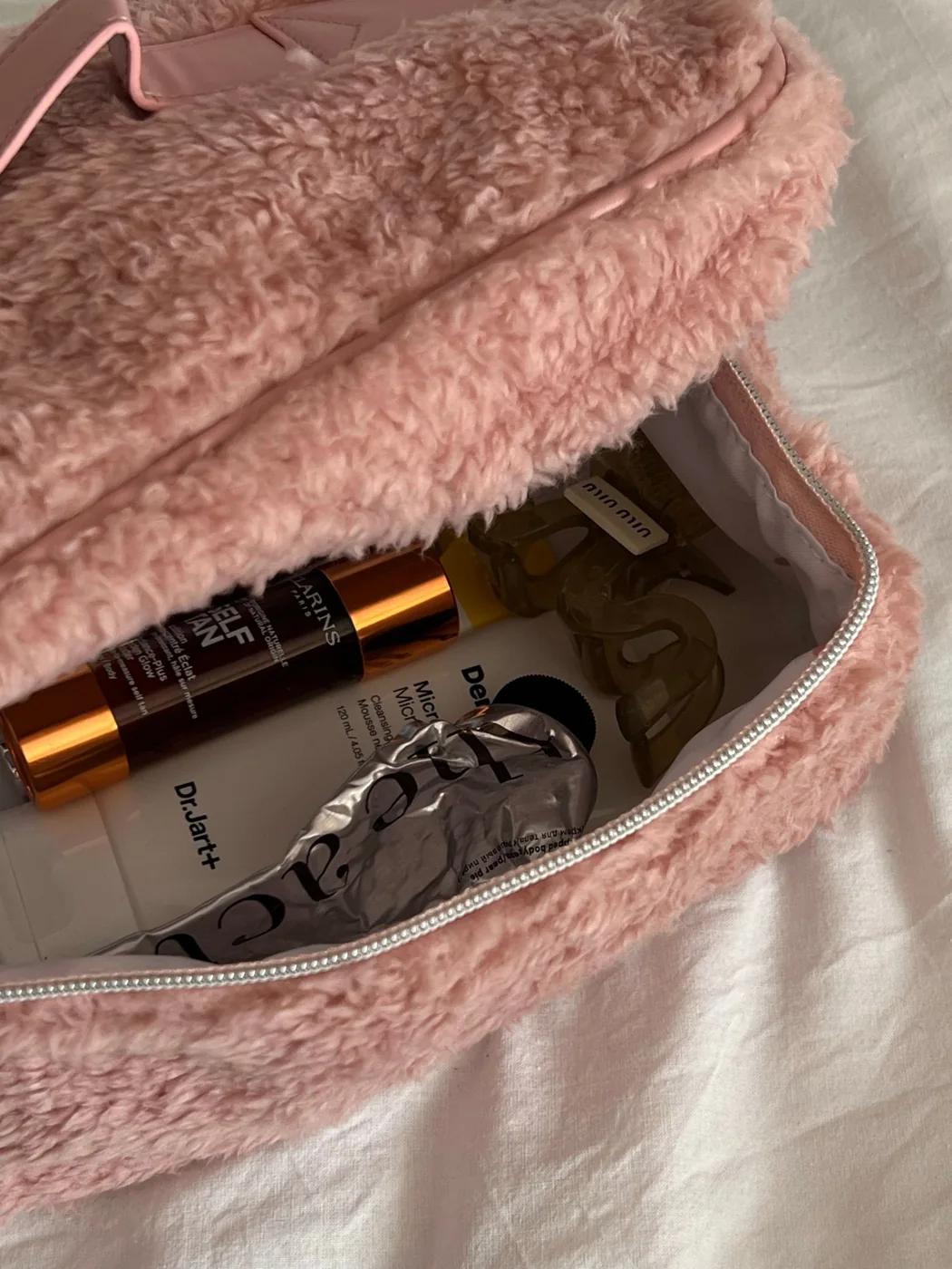 Skincare and cosmetics packed into a pink beauty bag