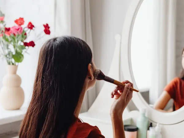 Woman doing makeup at a dressing table