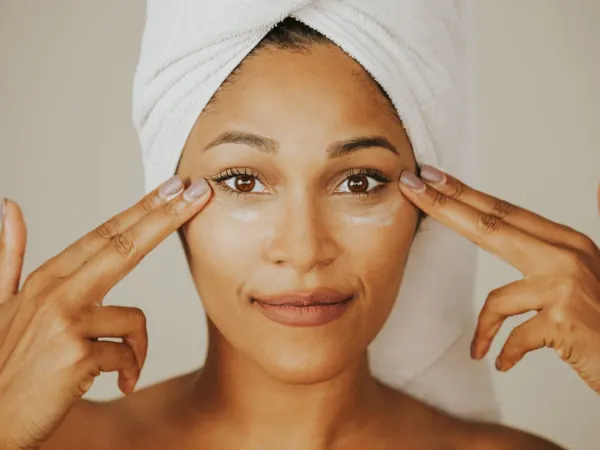 Woman with a towel around her hair applying facial cream