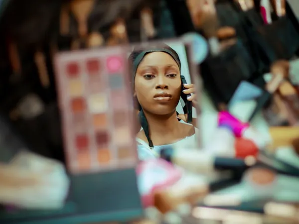 A reflection in a makeup mirror surrounded by cosmetics