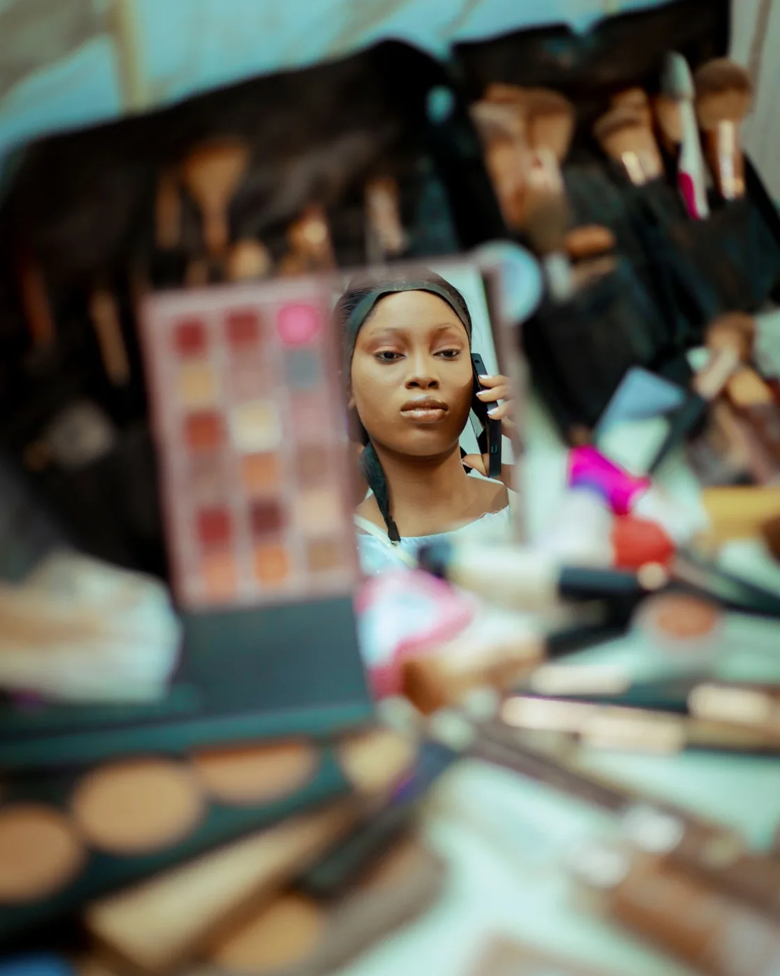 A reflection in a makeup mirror surrounded by cosmetics