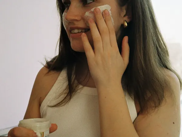 Woman applying facial cream at home
