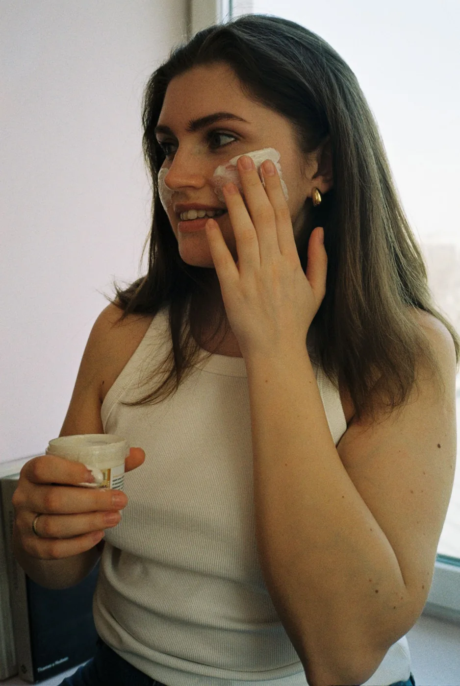Woman applying facial cream at home