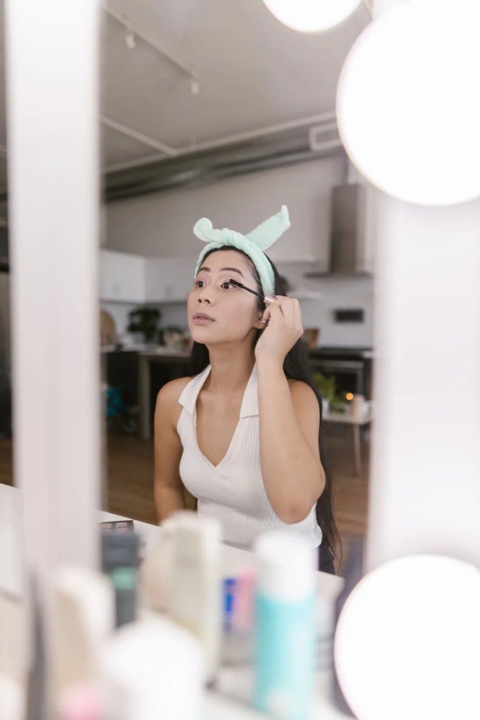 A woman using makeup tools at her mirror
