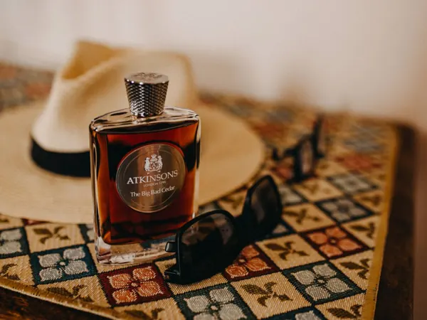 Perfume, a hat and sunglasses arranged on a table
