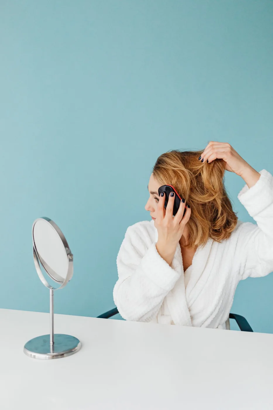 Woman using a small tabletop mirror to comb her hair