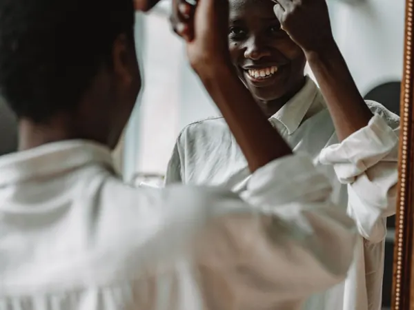 Woman smiling while applying makeup at a mirror