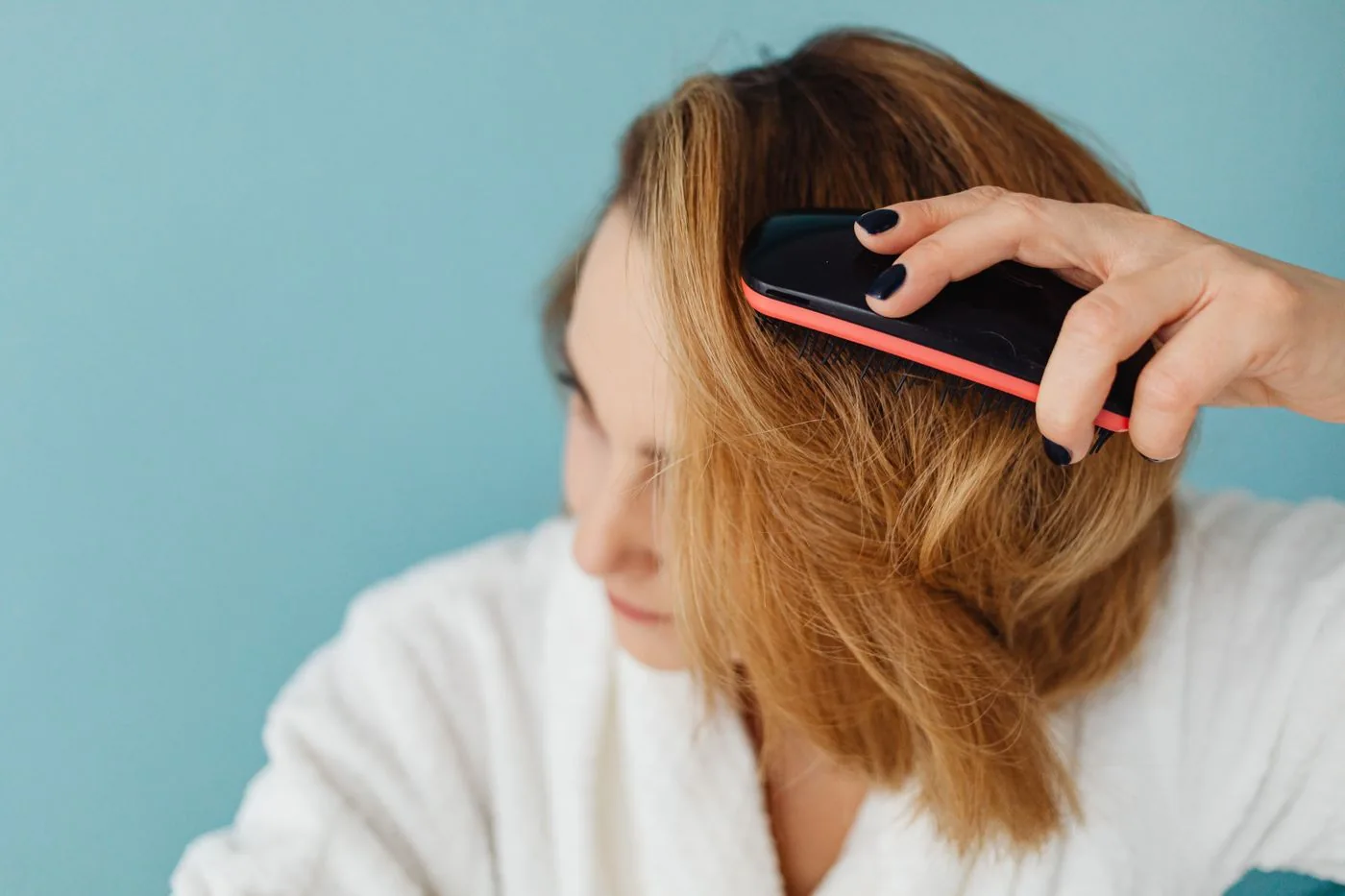 Woman in a bathrobe brushing her hair